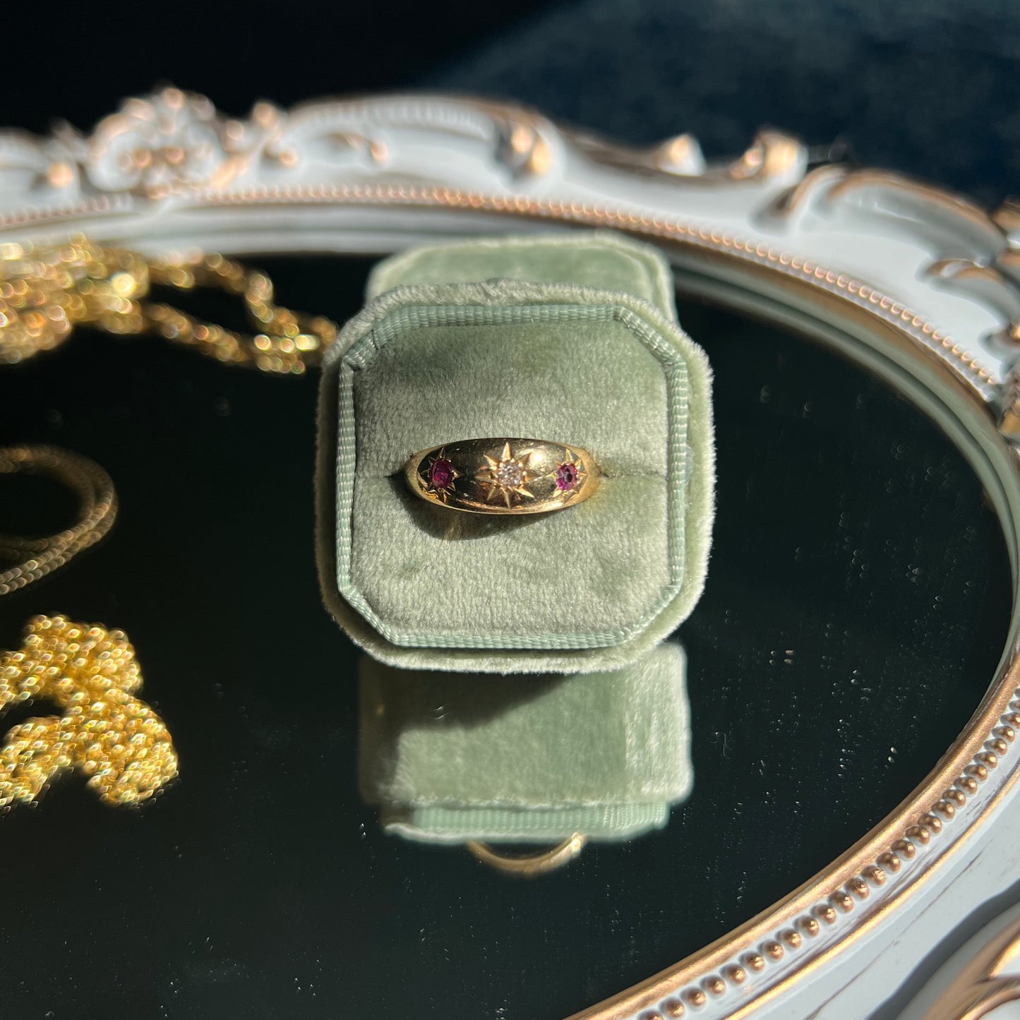 yellow gold ruby and diamond ring band in an light green ring box on top of a mirror