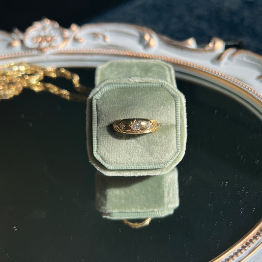 yellow gold ring band with diamonds in a light green ring box on top of a mirror